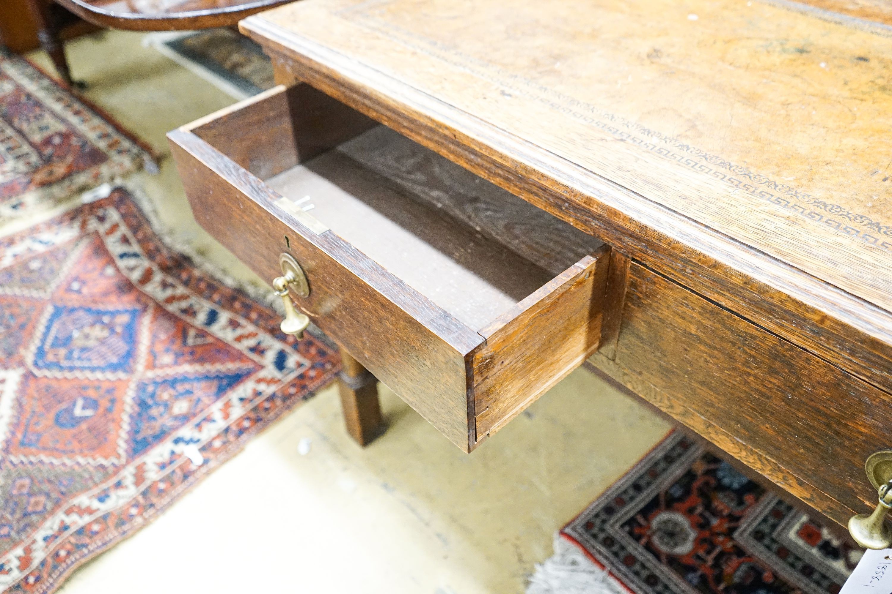A 1920's oak two drawer writing table, with a leather inset top, length 106cm, depth 52cm, height 75cm